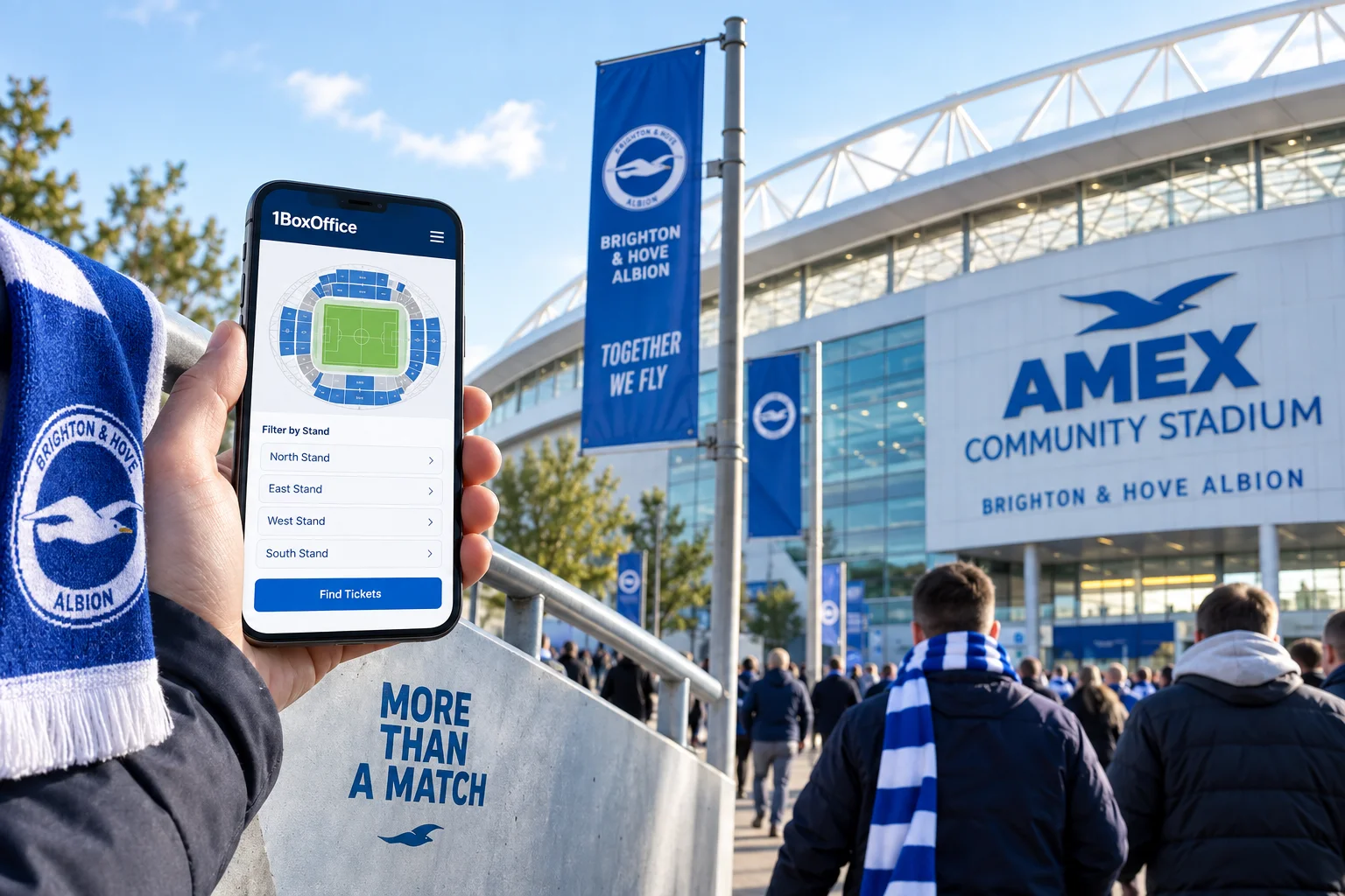 A hand holding a smartphone displaying the 1BoxOffice ticket booking interface with a stadium seating map, held in front of crowds entering the American Express Community Stadium.