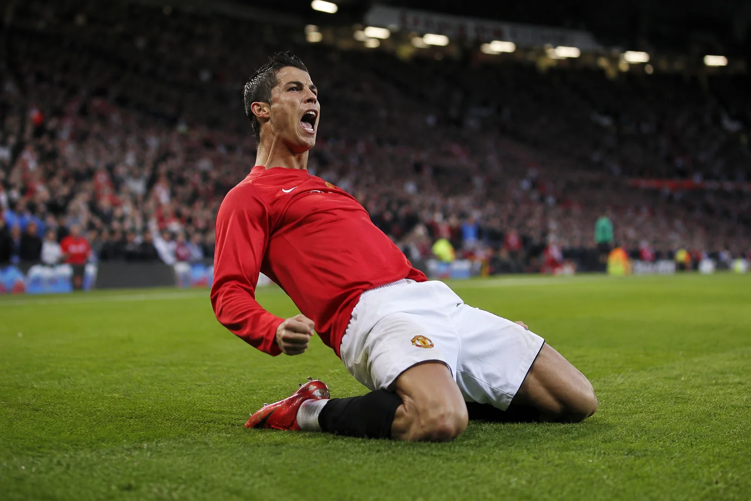 An infographic documenting Cristiano Ronaldo's initial legendary stint at Manchester United under Sir Alex Ferguson. The left side features a dynamic action shot of a young, blonde-highlighted Ronaldo yelling in celebration while wearing the classic red Vodafone-sponsored United home kit. The background showcases a packed Old Trafford stadium layout with a large club devil emblem. The right side lists his major achievements between 2003 and 2009, including three Premier League titles, his first UEFA Champions League trophy, and his first Ballon d'Or in 2008.