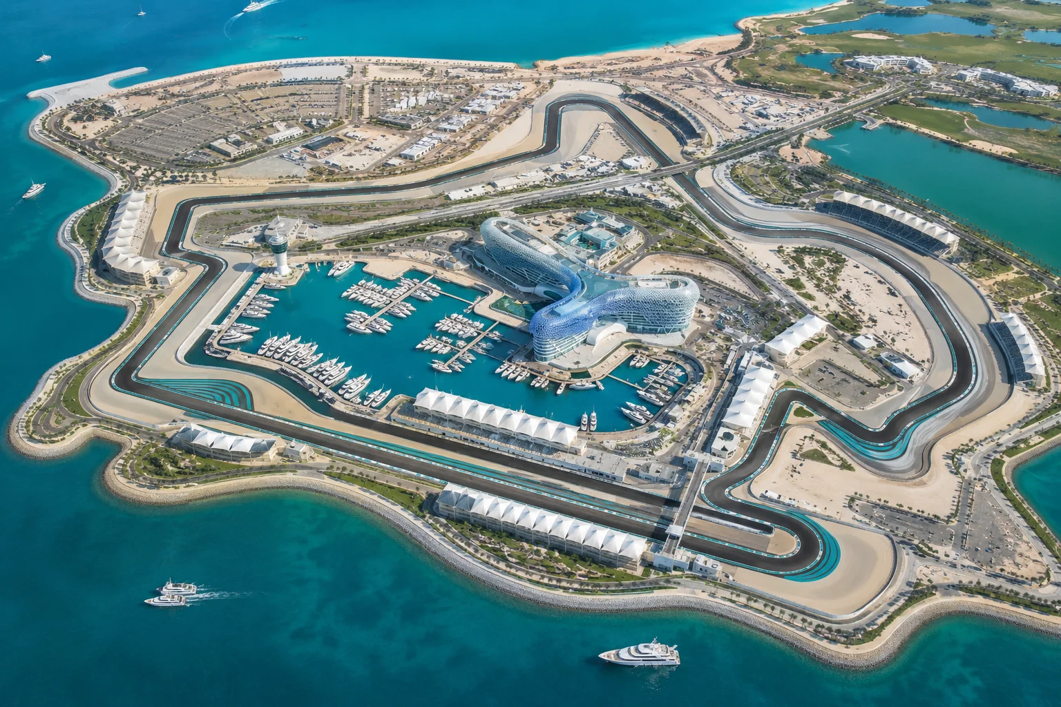 An aerial view showing the entirety of Yas Island and the Yas Marina Circuit layout, highlighting the winding race track surrounding the central marina packed with yachts, the hotel complex, and the turquoise waters of the Arabian Gulf.