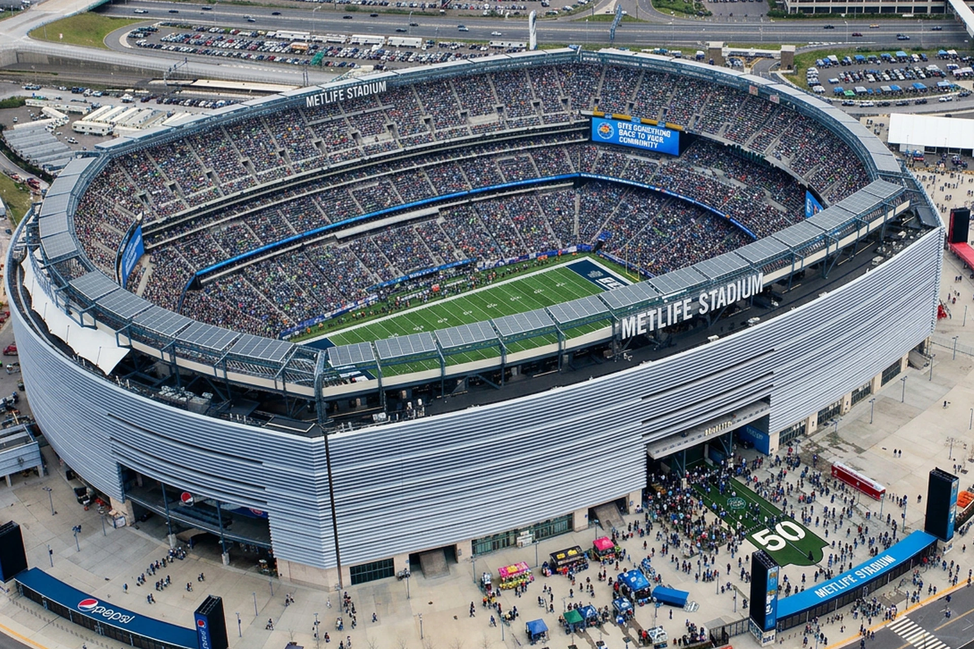 عرض جوي لاستاد MetLife يظهر الباحة الكاملة، الملعب والمنطقة المحيطة بيوم المباراة.