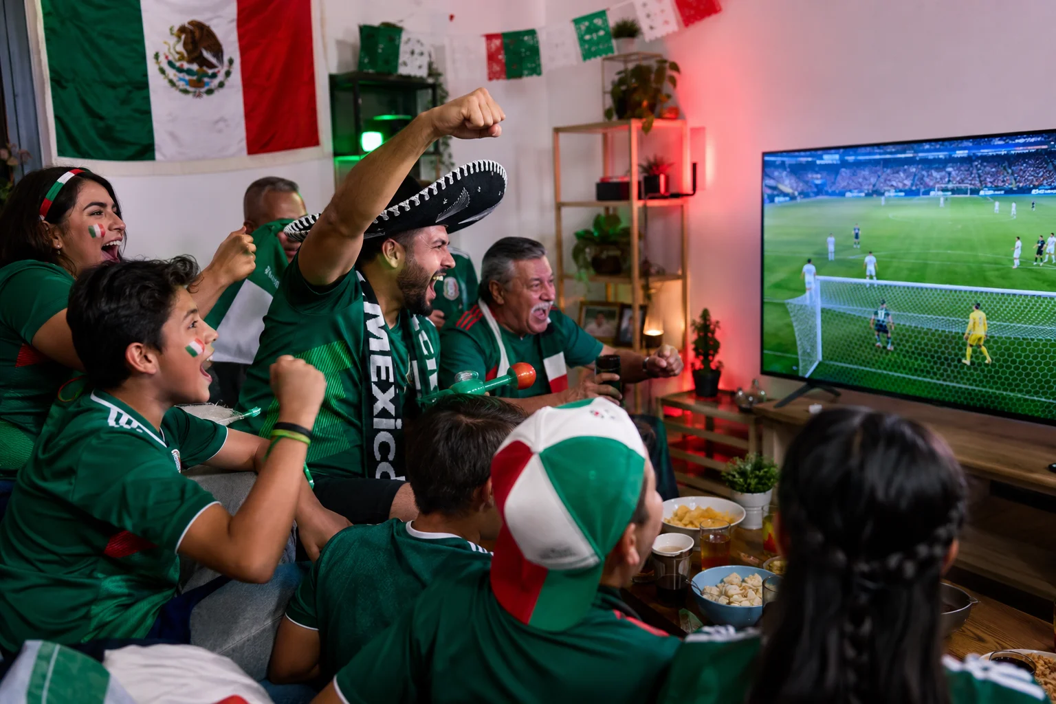 مشجعو المكسيك يشجعون في قمصان خضراء أثناء مشاهدة كأس العالم 2026 على التلفزيون في المنزل