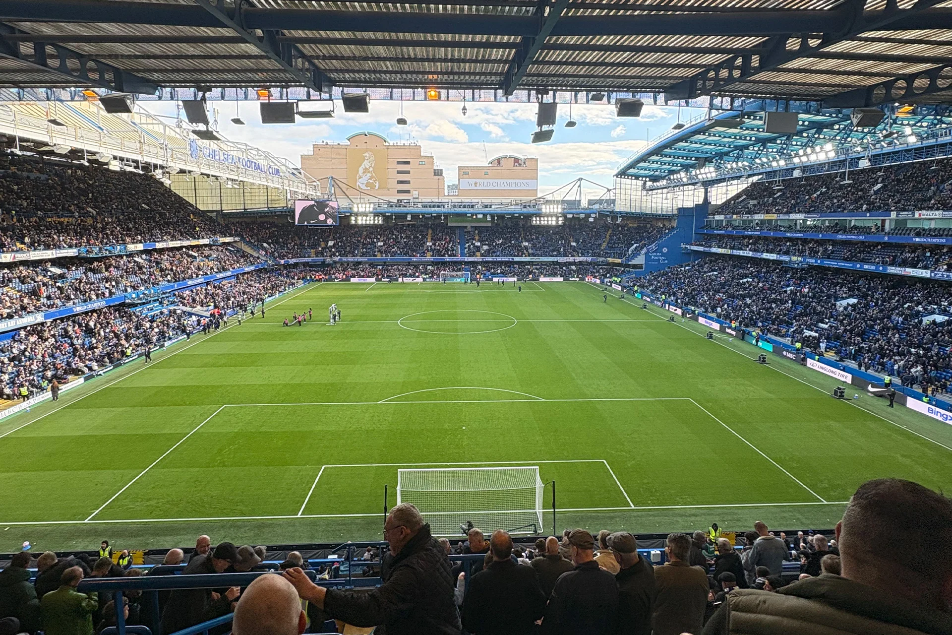 Stamford Bridge matchday view from the stands with the pitch, fans and Chelsea FC banners.