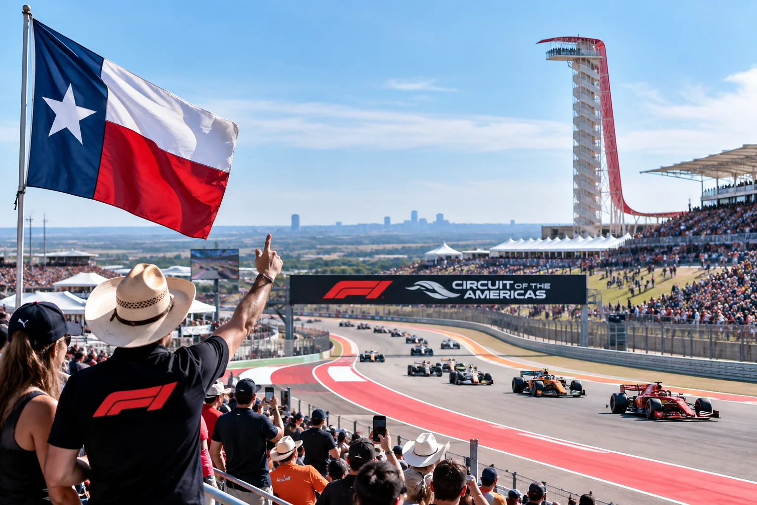 Fans in grandstands watching Formula 1 cars race along Turn 1 at COTA with a Texas flag flying in the foreground and the observation tower in the distance.